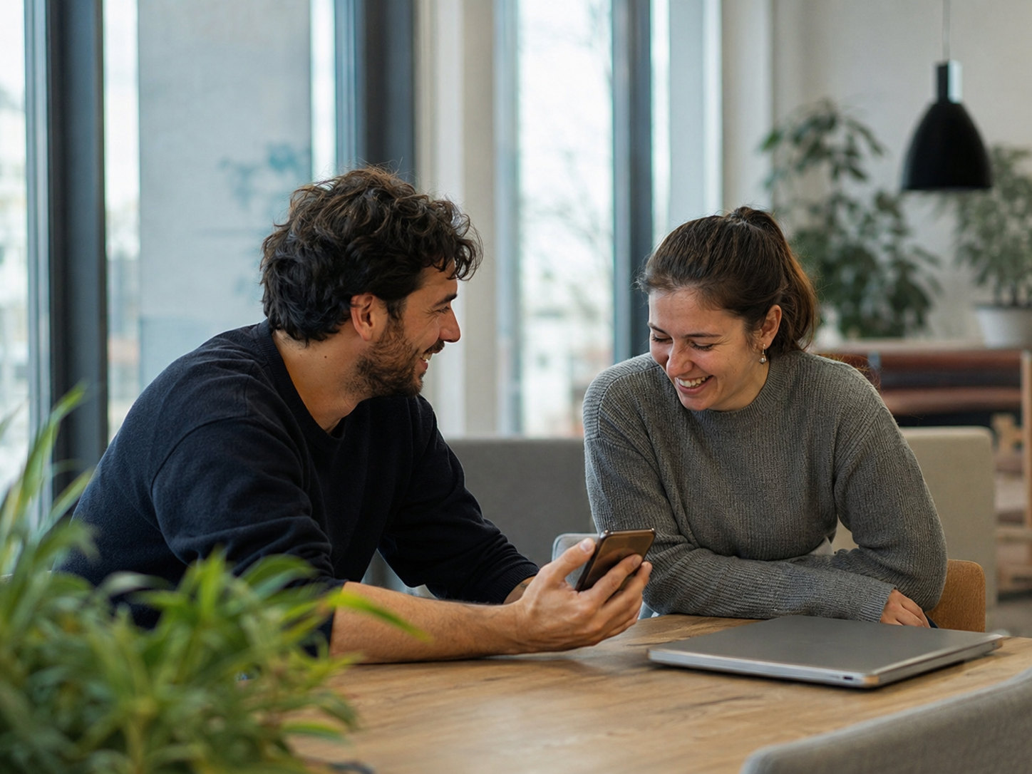 Two Supertree members at a table by the window, one showing the other a referral link on a phone