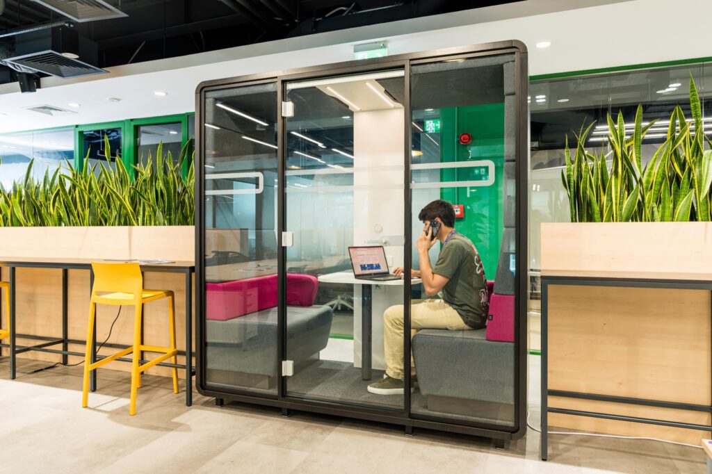 A Supertree desk member taking a call in a phone booth beside the coworking area